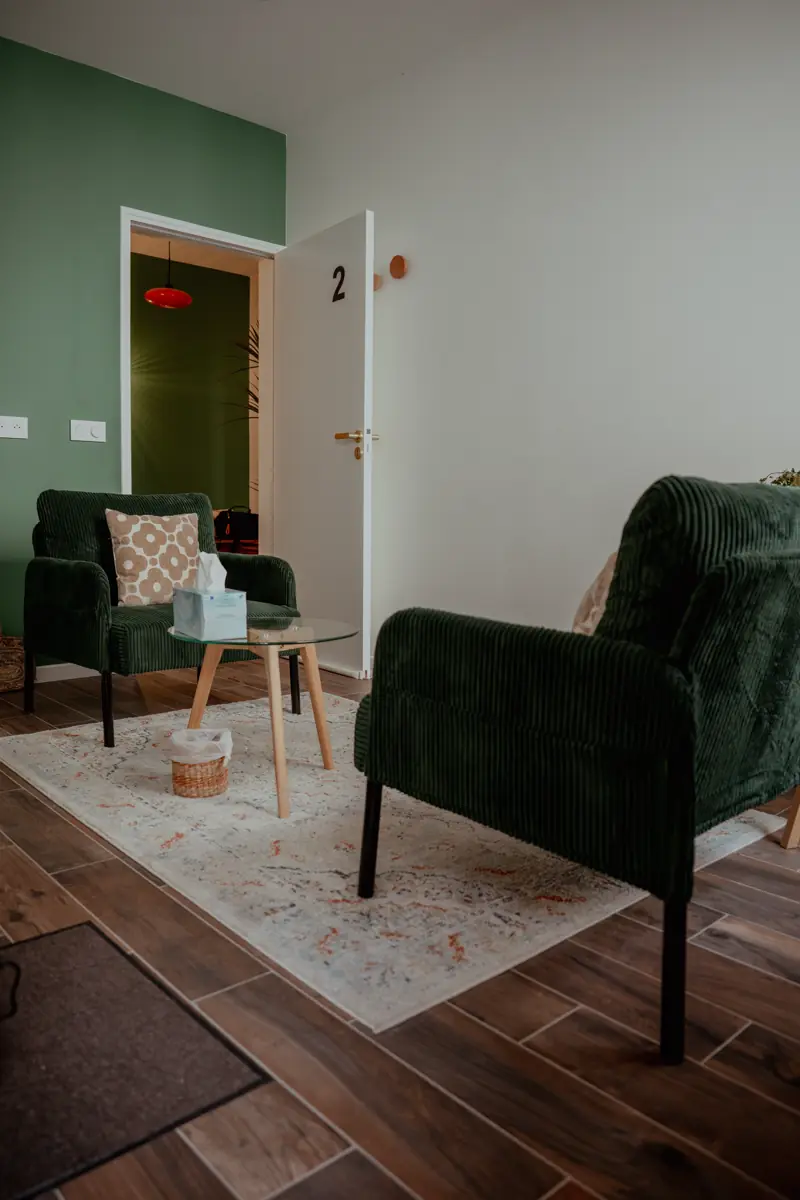 Le cabinet : deux fauteuils en velours vert disposés en face à face, un petit guéridon et un tapis clair.